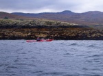 Chris paddling past typical wild coastline